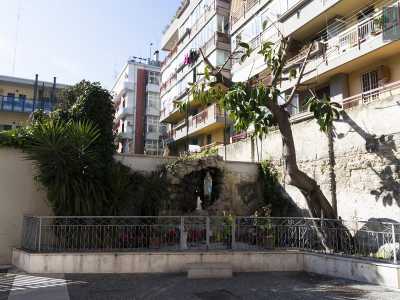 Usciamo dall�istituto e in un angolo del vicolo protetta da una bassa ringhiera in ferro troviamo la grotta votiva della Madonna di Lourdes sulla quale ogni giorno i fedeli portano fiori freschi e si fermano qualche istante per pregare